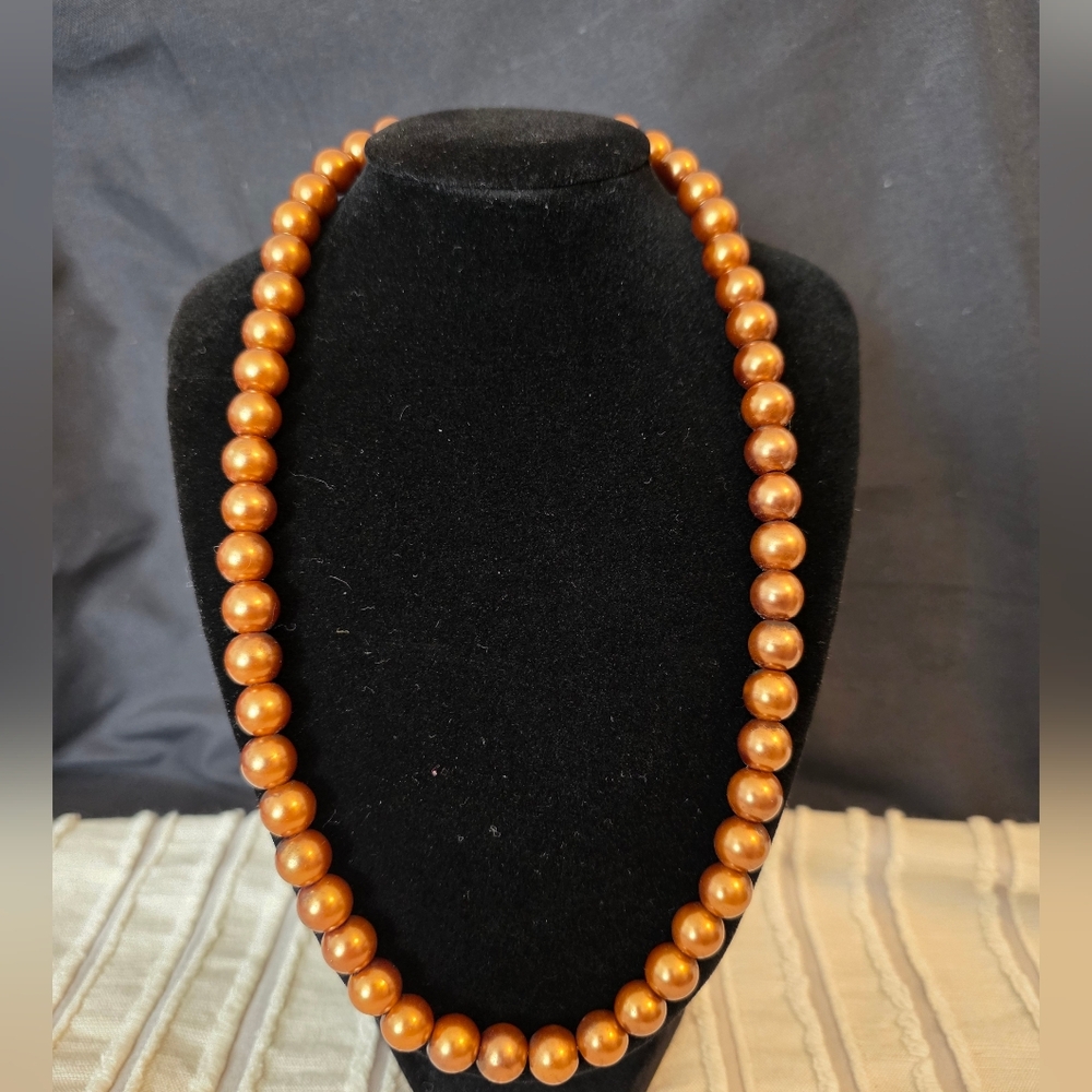Elegant single-strand necklace featuring bronze-toned faux or cultured pearls